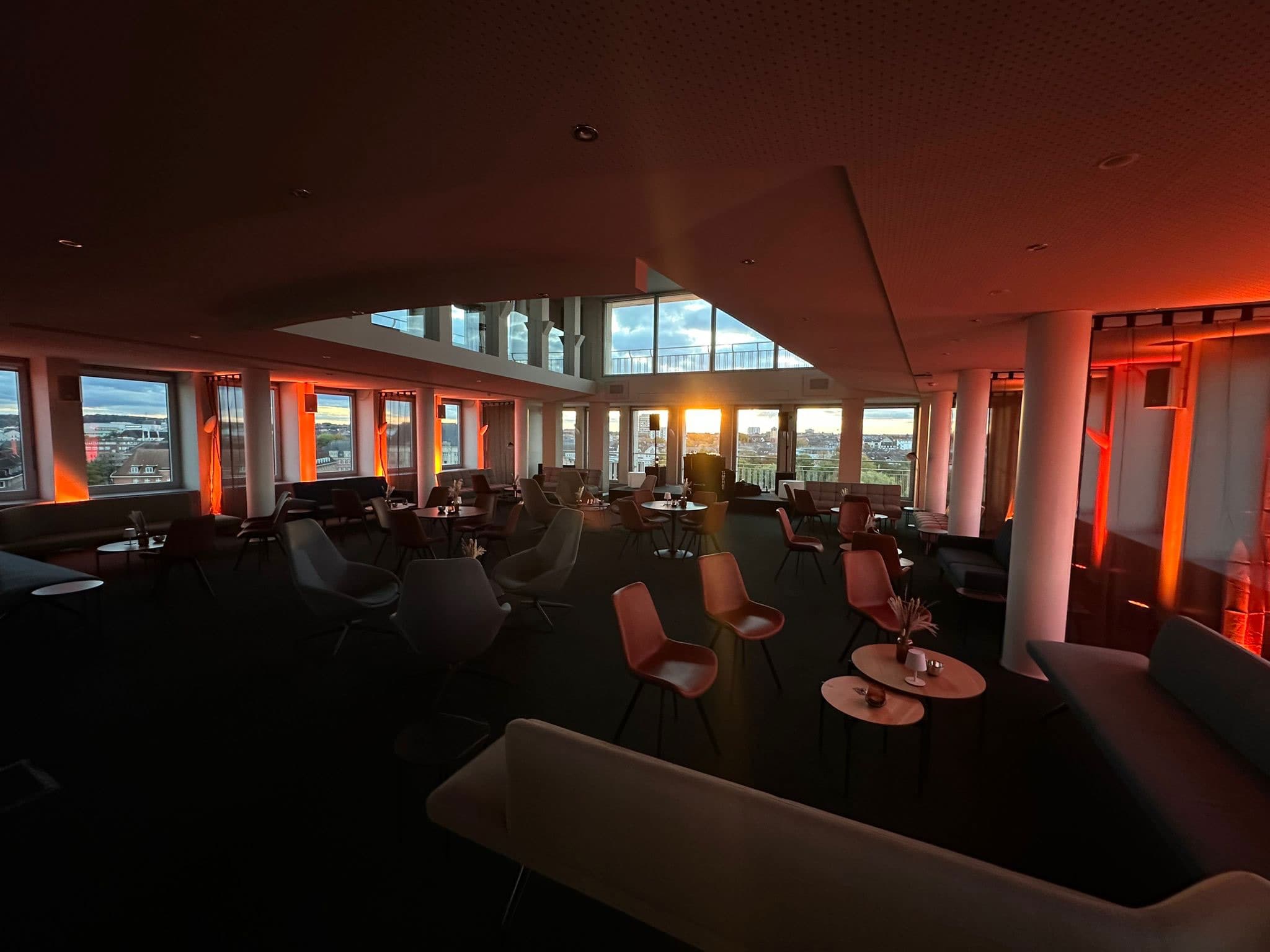 Rooftop-Lounge im historischen Bankgebäude mit Blick über Kiel, warmes Licht.